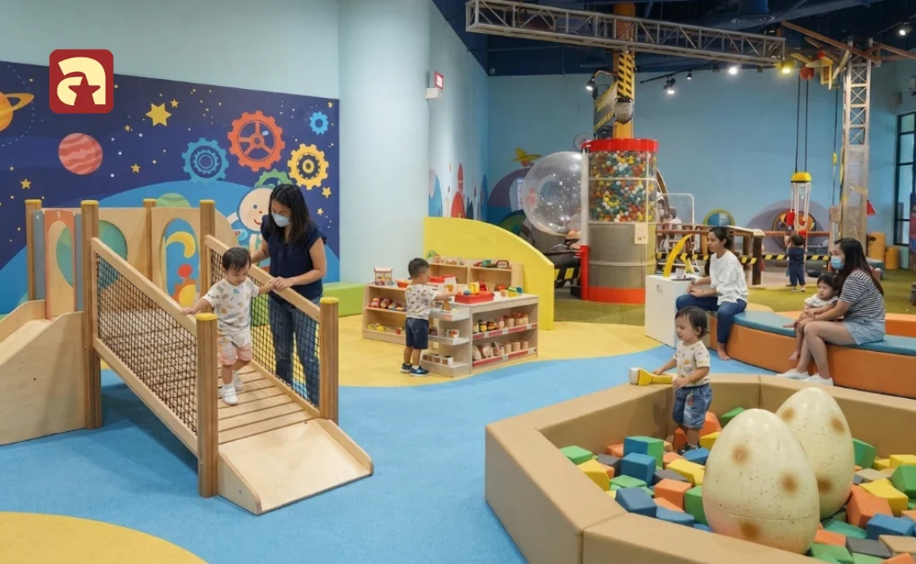 Toddlers playing on wooden bridge and dino pit at KidsSTOP science center play area in Singapore
